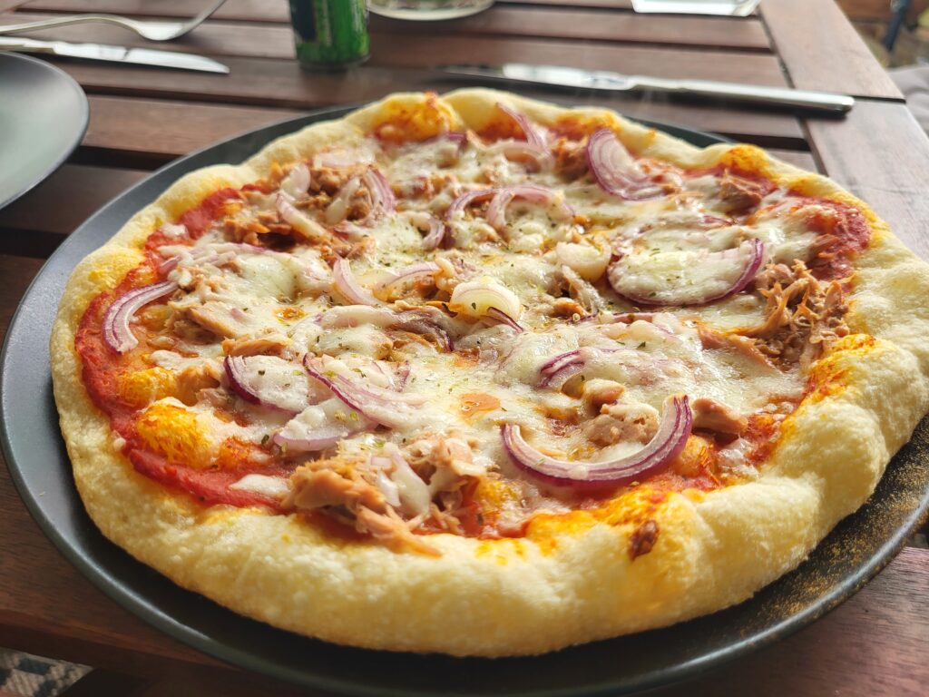 Eine Pizza belegt mit Zwiebeln, Tunfisch und Käse. 